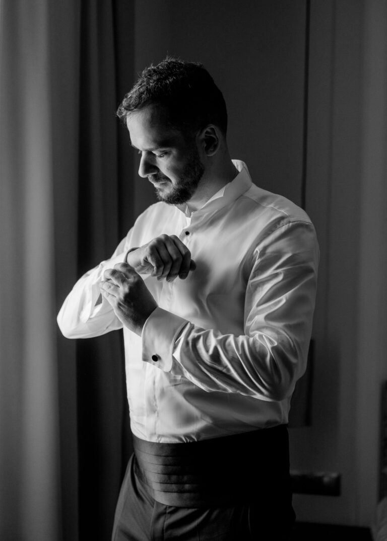 Pan młody zapinający mankiety koszuli przed ślubem w Pałacu Suchary